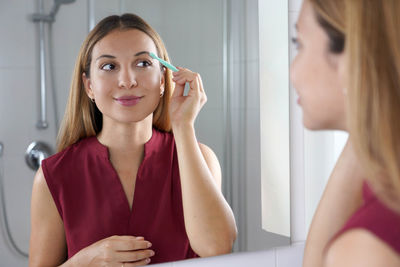 Pretty woman using razor on bathroom. beautiful young woman shaving her face by razor at home.