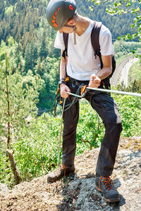 Full length of boy holding rope while standing on rock