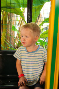 Cute boy looking away while sitting in toy train