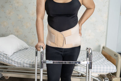 Low section of woman standing on bed