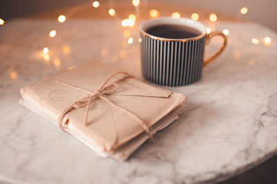 Cup of coffee with pile of paper handwritten letters stay on marble table in room over glow lights