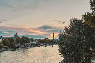 River amidst buildings against sky during sunset