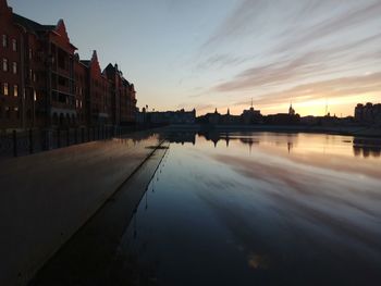 River by city against sky at sunset