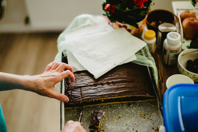 Cropped hand cutting cake in home