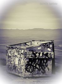 Graffiti on wall by sea against sky