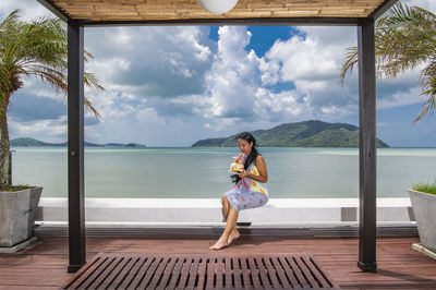 Beautiful woman enjoying coconut juice on rooftop of luxury resort