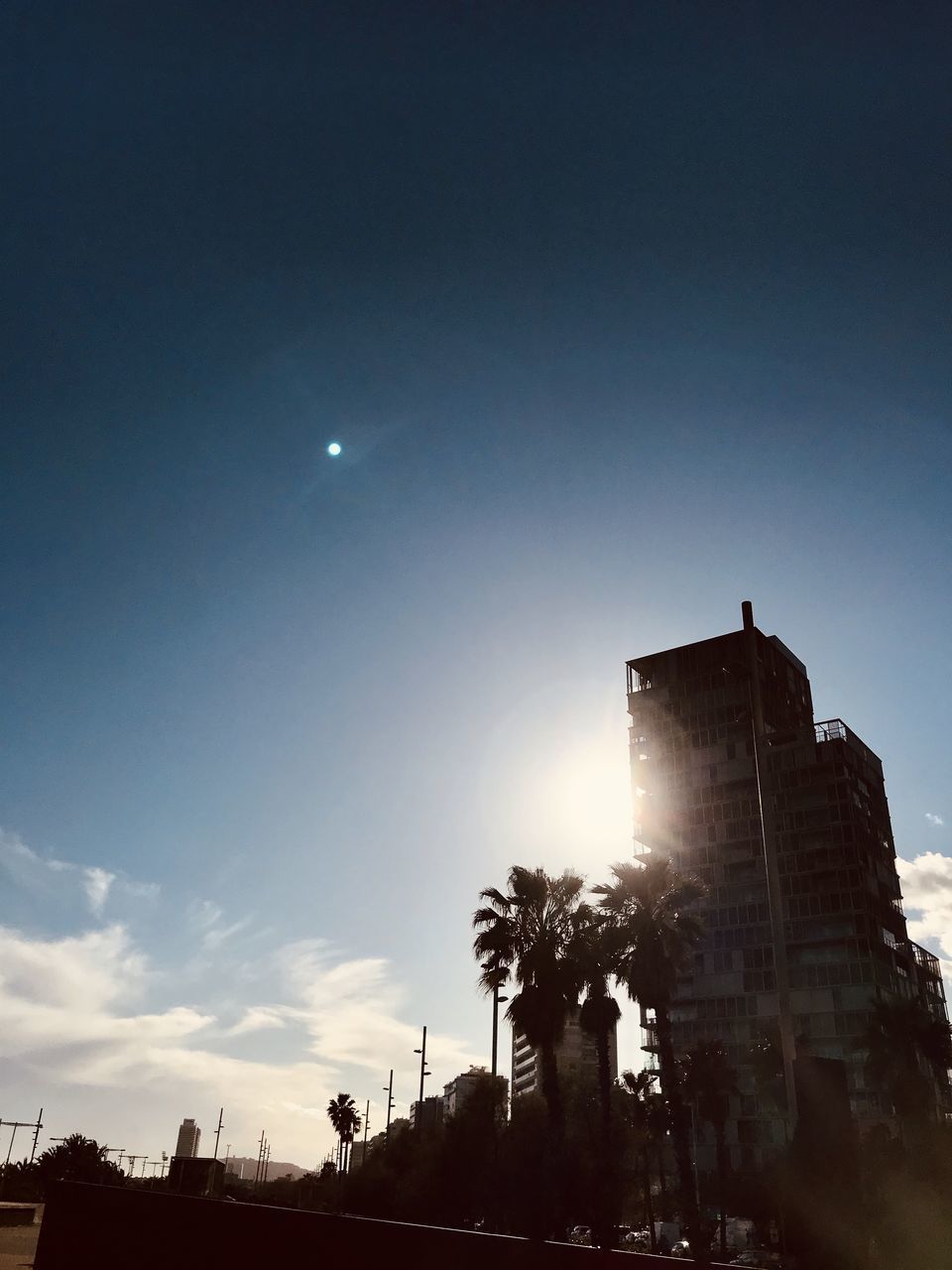 LOW ANGLE VIEW OF BUILDINGS AGAINST BRIGHT SUN