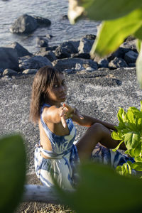 Young woman drinking water while sitting at beach