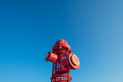 A giant red fire hydrant at a dog park on a clear sky