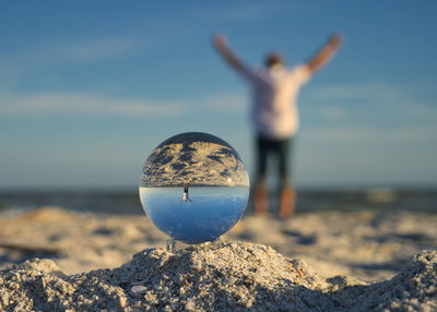 Reflection of rocks in water on rock at beach against sky