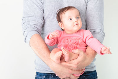 Midsection of father carrying baby girl against white background