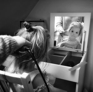 Cropped hand of mother drying daughter hair