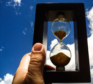 Close-up of hand holding glass against sky