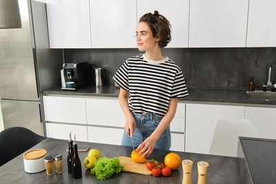 Portrait of young woman standing in kitchen