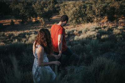 Couple holding hands while walking on field