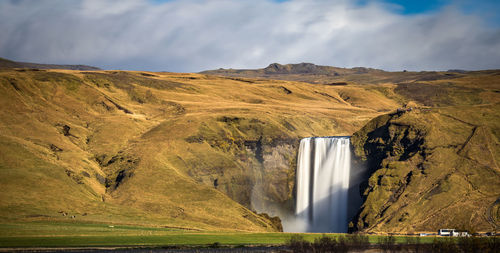 Scenic view of waterfall against cloudy sky