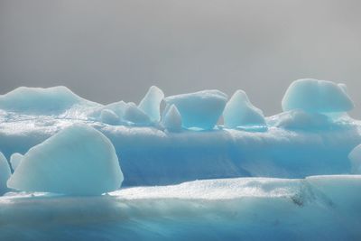 Ice floating on water against sky during winter