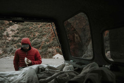 Man in warm clothing eating banana seen through off-road vehicle