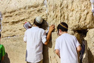 Friends praying against wall