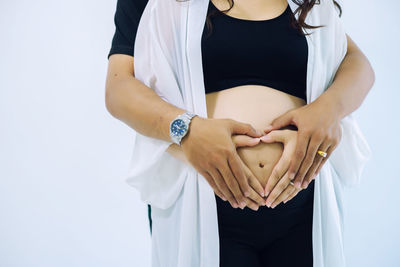 Midsection of woman standing against white background