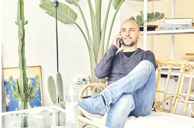 Young man using phone while sitting on table