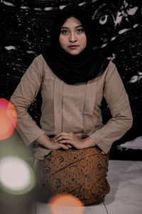 Portrait of young woman wearing hijab while sitting at home