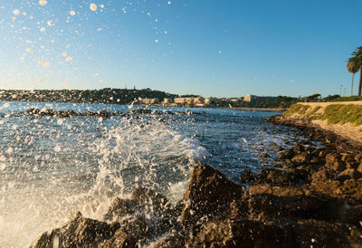 Sea waves splashing on rocks against clear sky