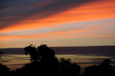 Silhouette trees by sea against romantic sky at sunset