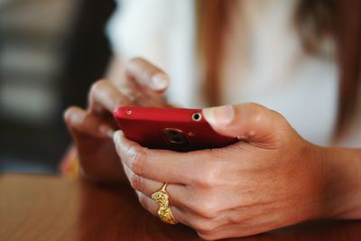 Close-up midsection of woman using phone on desk