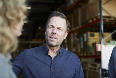 Mature male worker looking at female colleague at warehouse