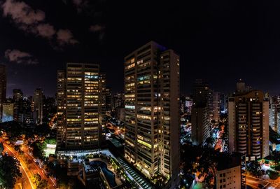 Illuminated buildings in city against sky at night