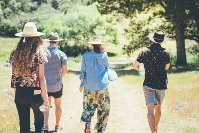 Rear view of people walking along plants