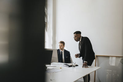 Businessmen planning strategy over desktop pc at desk in office