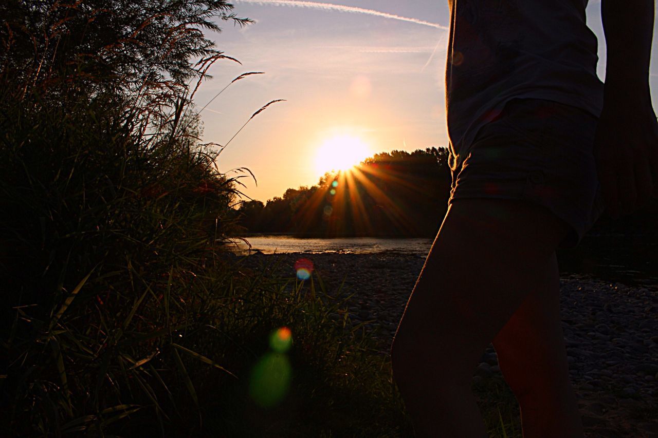 sun, low section, sunlight, sunbeam, sunset, lens flare, sky, nature, person, lifestyles, beauty in nature, unrecognizable person, tranquility, water, leisure activity, tranquil scene, scenics