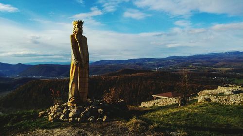 Statue in a field with mountain range in background