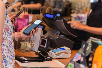 Woman paying bill through smartphone using nfc technology in a restaurant