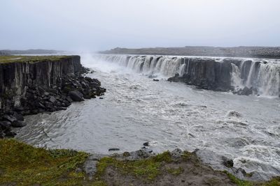 Scenic view of waterfall against sky