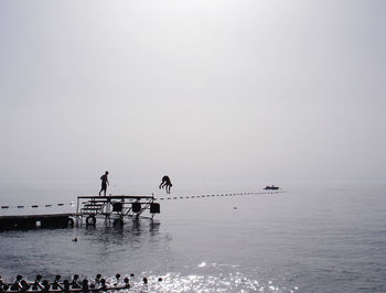 People in sea against clear sky