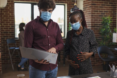 Business colleagues wearing mask brainstorming in office