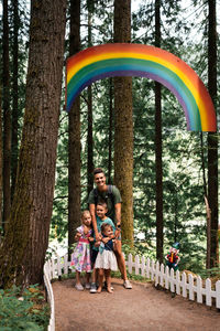 Children and mother under rainbow in forest