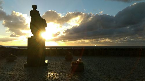 Silhouette man standing by sea against sky during sunset