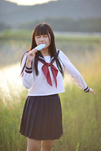 Young woman with arms raised standing against sky