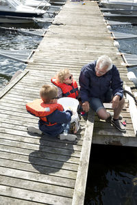 Man sitting on jetty with grandchildren