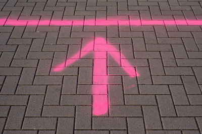 Pink painted arrow on pavement