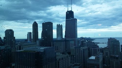 Skyscrapers in city against cloudy sky