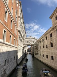 Canal amidst buildings in city against sky