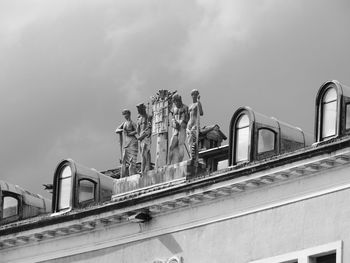 Low angle view of sculpture by building against sky