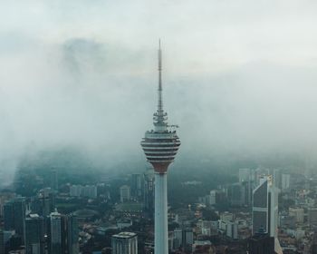 Communications tower in city against sky