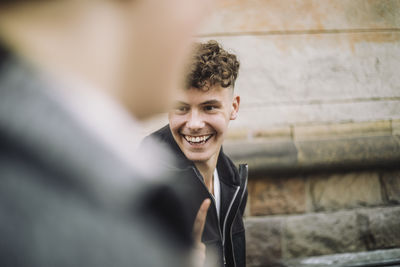 Happy boy with curly hair laughing while walking at street