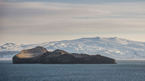 Scenic view of sea by mountains against sky